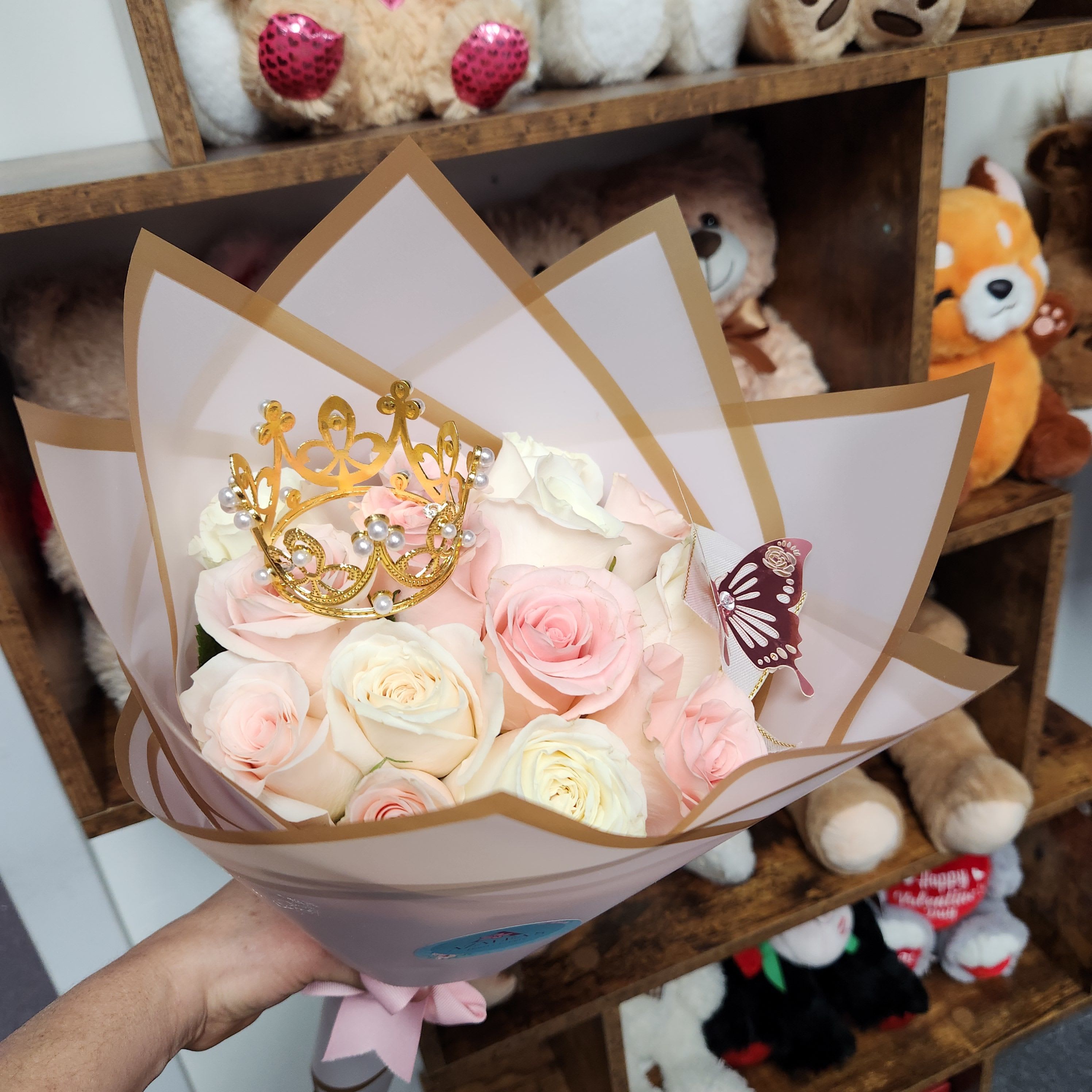 Bouquet of pale pink and white roses with a gold crown topper
