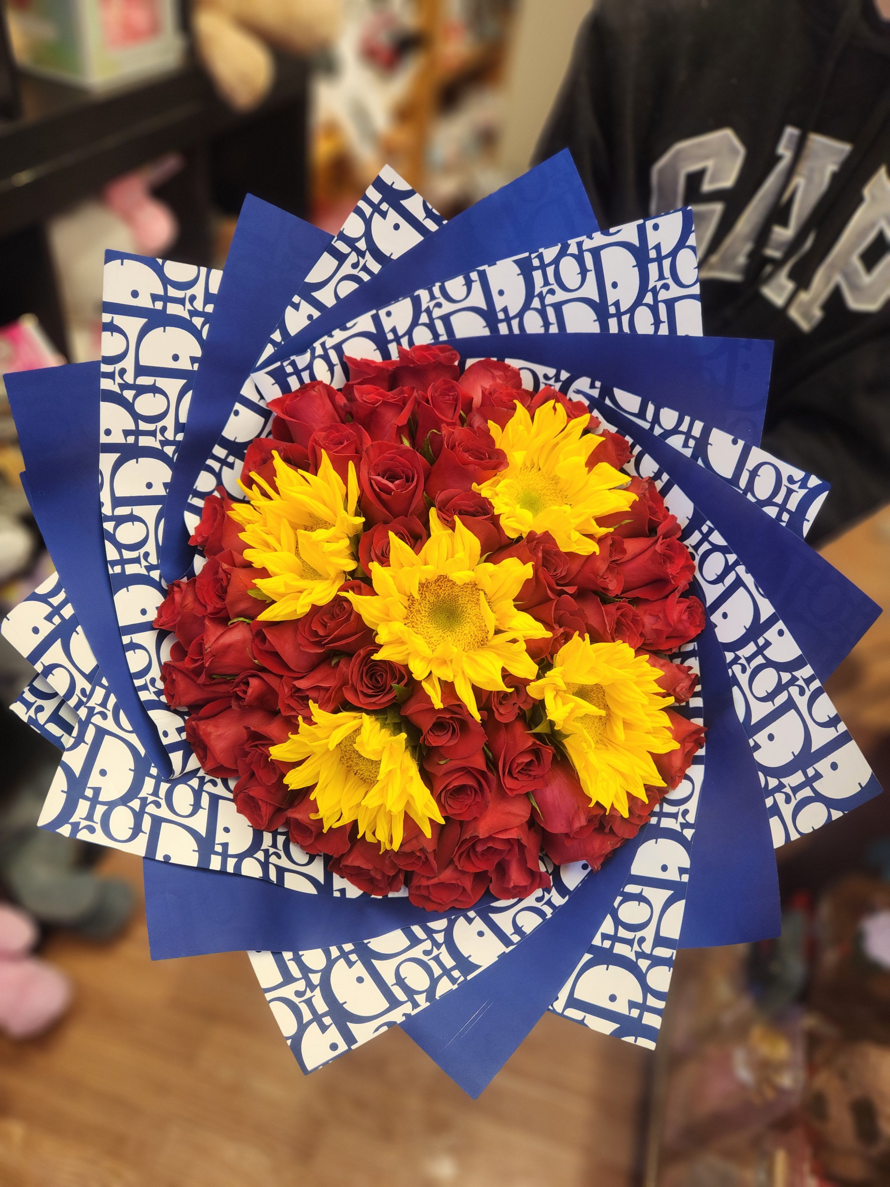Bouquet of red roses with yellow sunflowers wrapped in blue paper