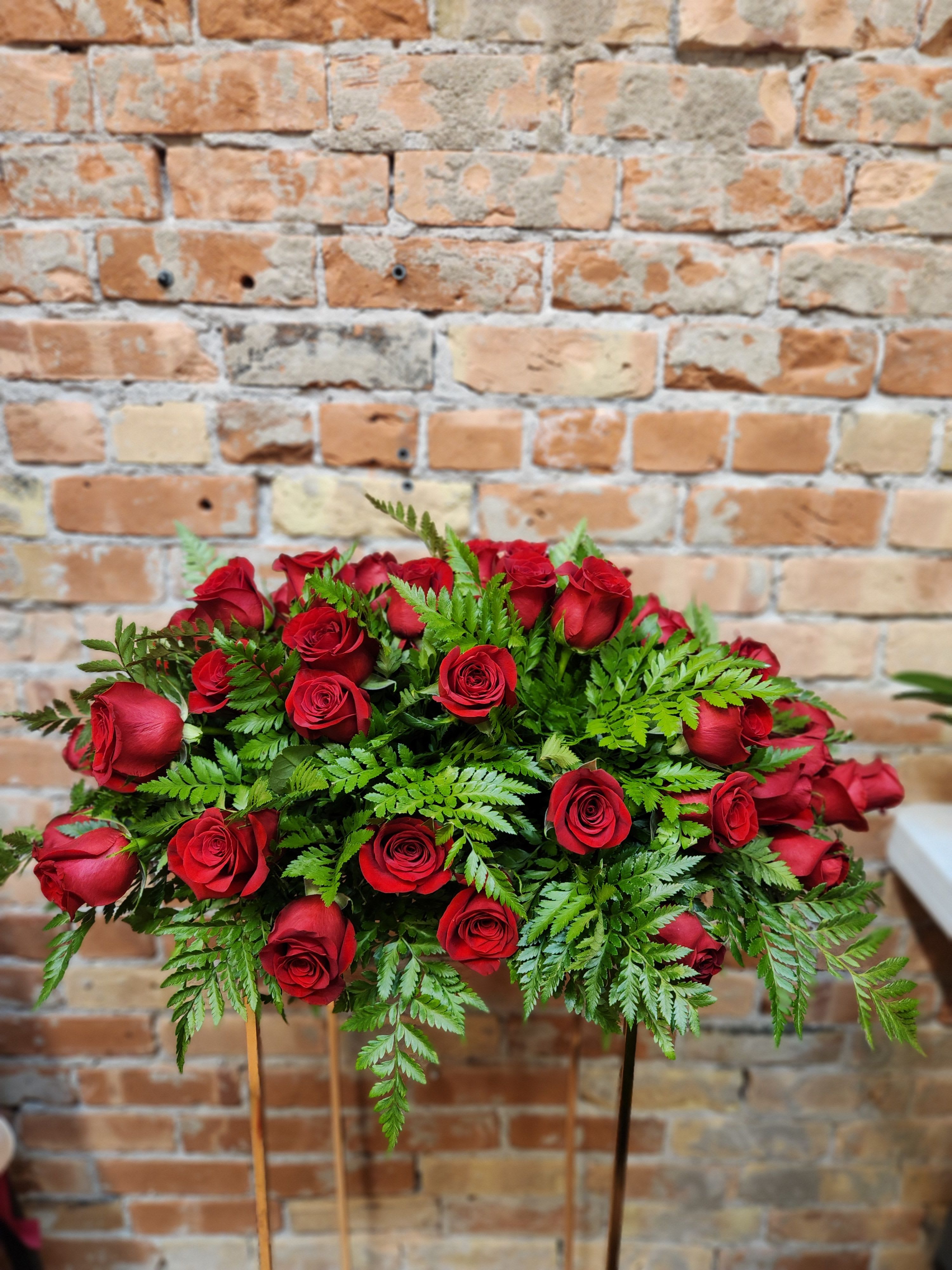 Red roses arranged in a low spray with fern foliage