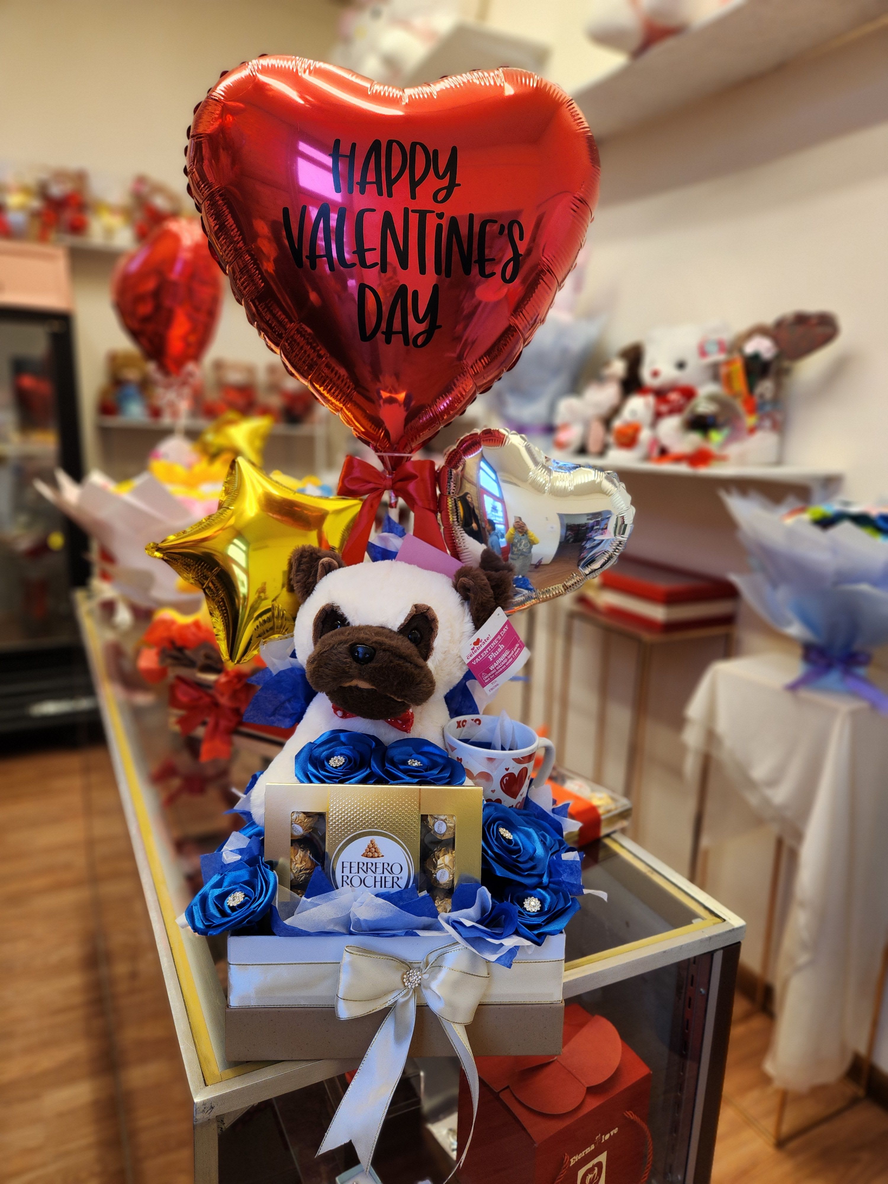 Valentine's gift arrangement with heart balloons, a plush dog, and chocolates