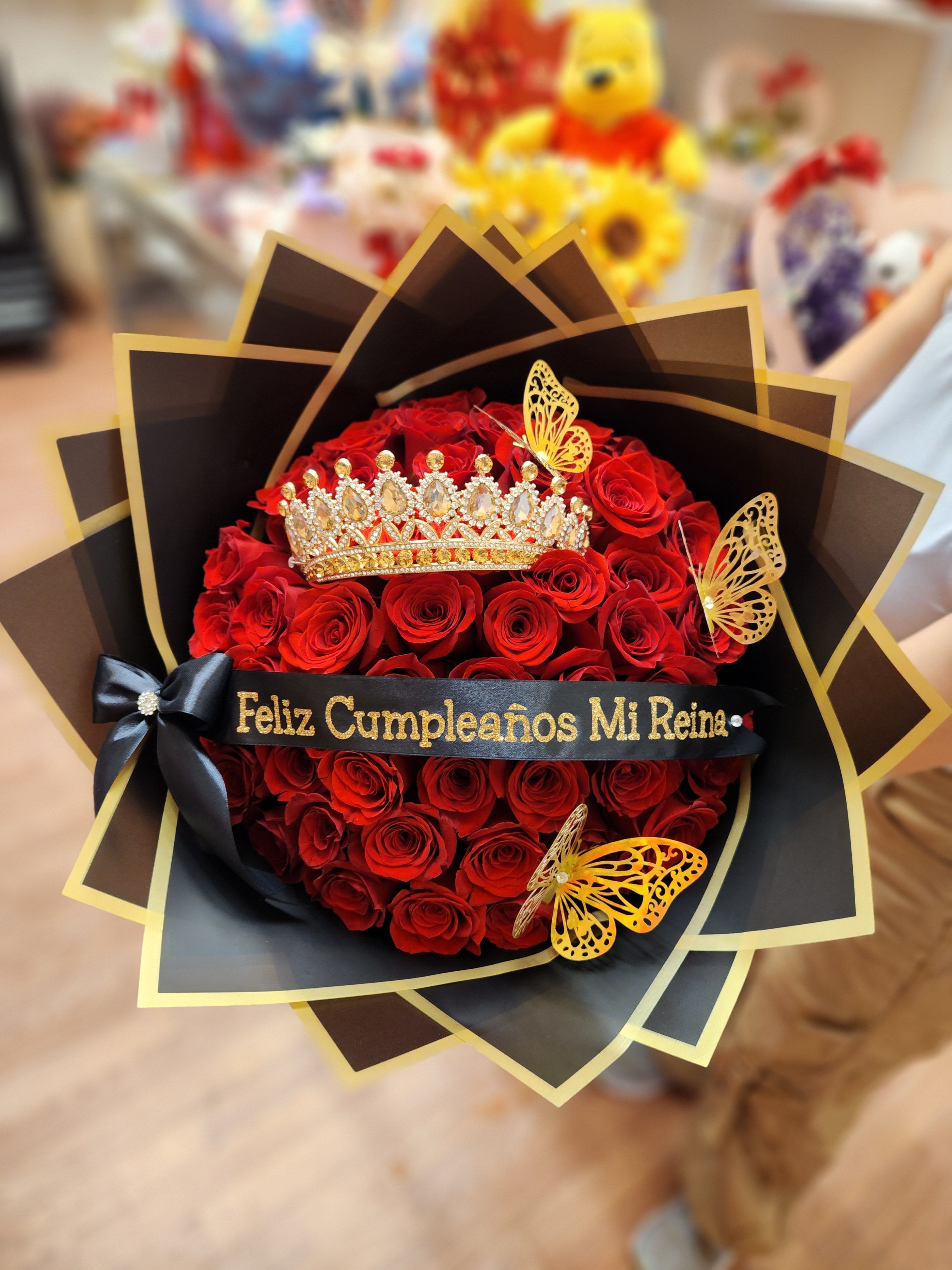 Red rose bouquet with a jeweled crown and black-and-gold wrapping