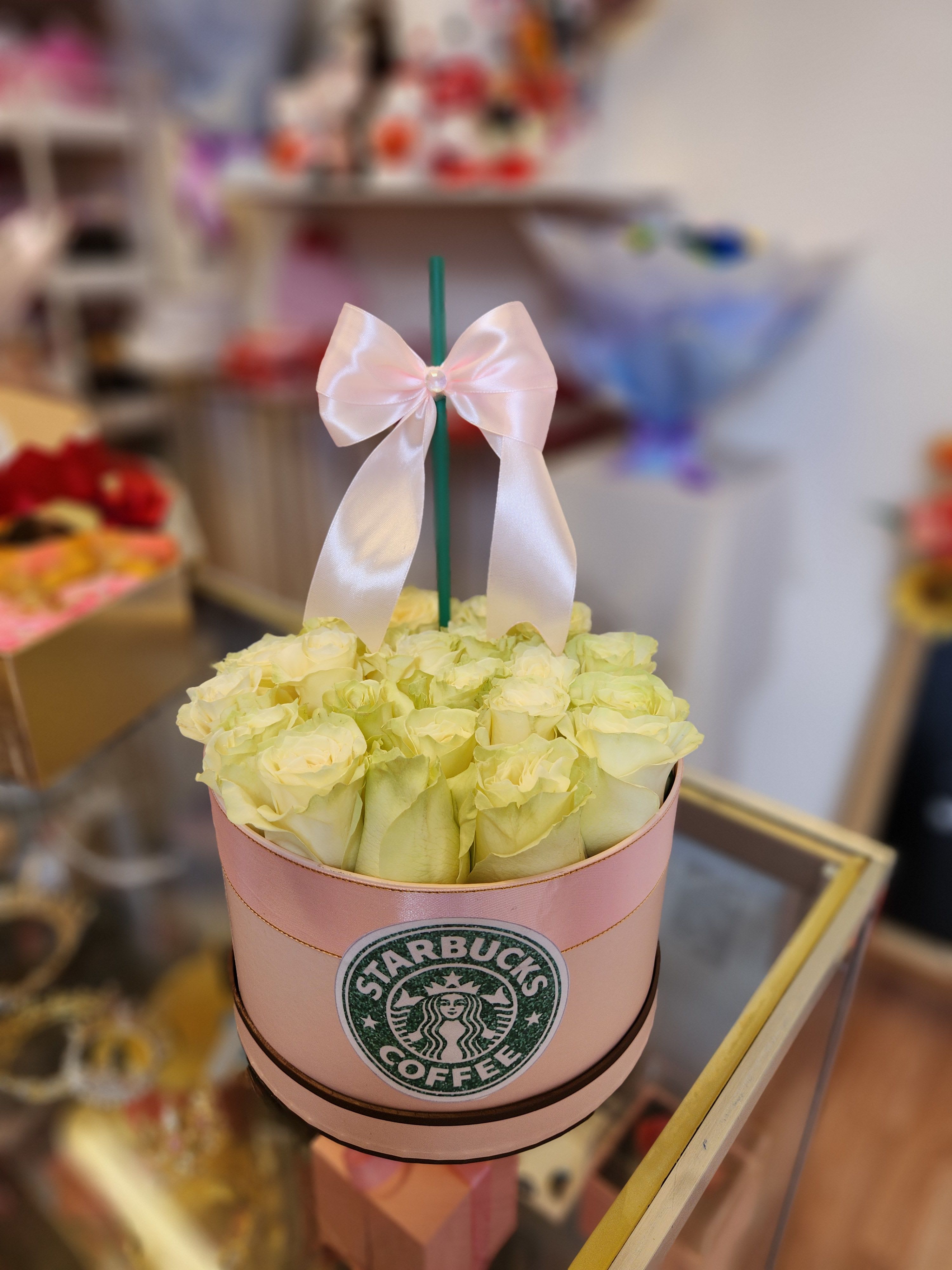 A pink box of pale yellow roses with a white ribbon bow
