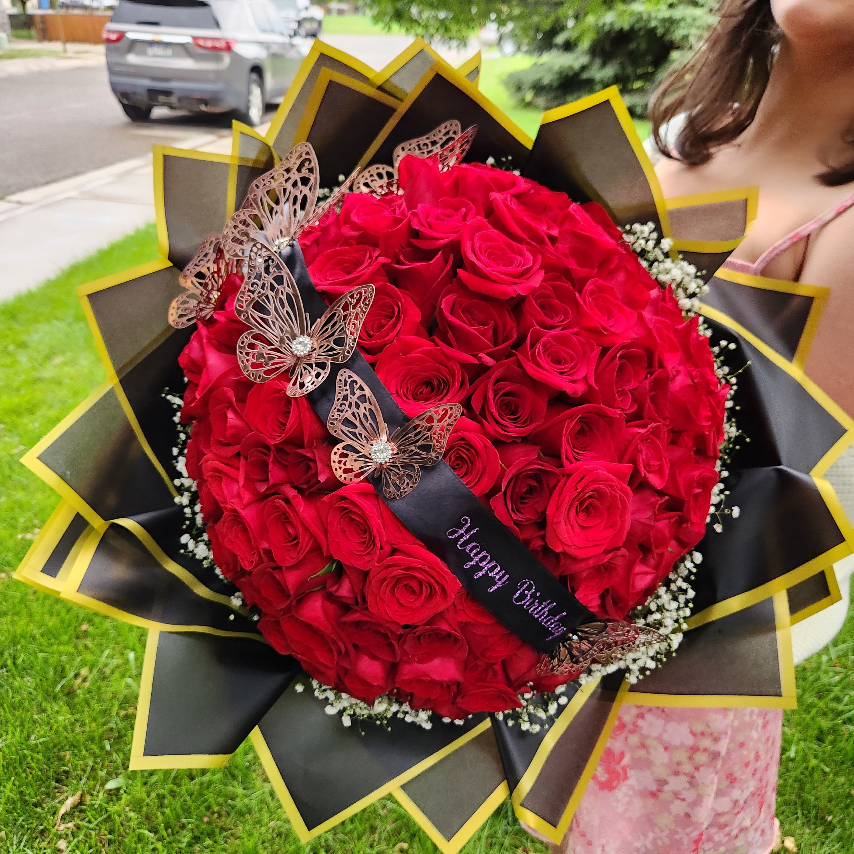 Large bouquet of red roses with butterfly decorations and a birthday ribbon