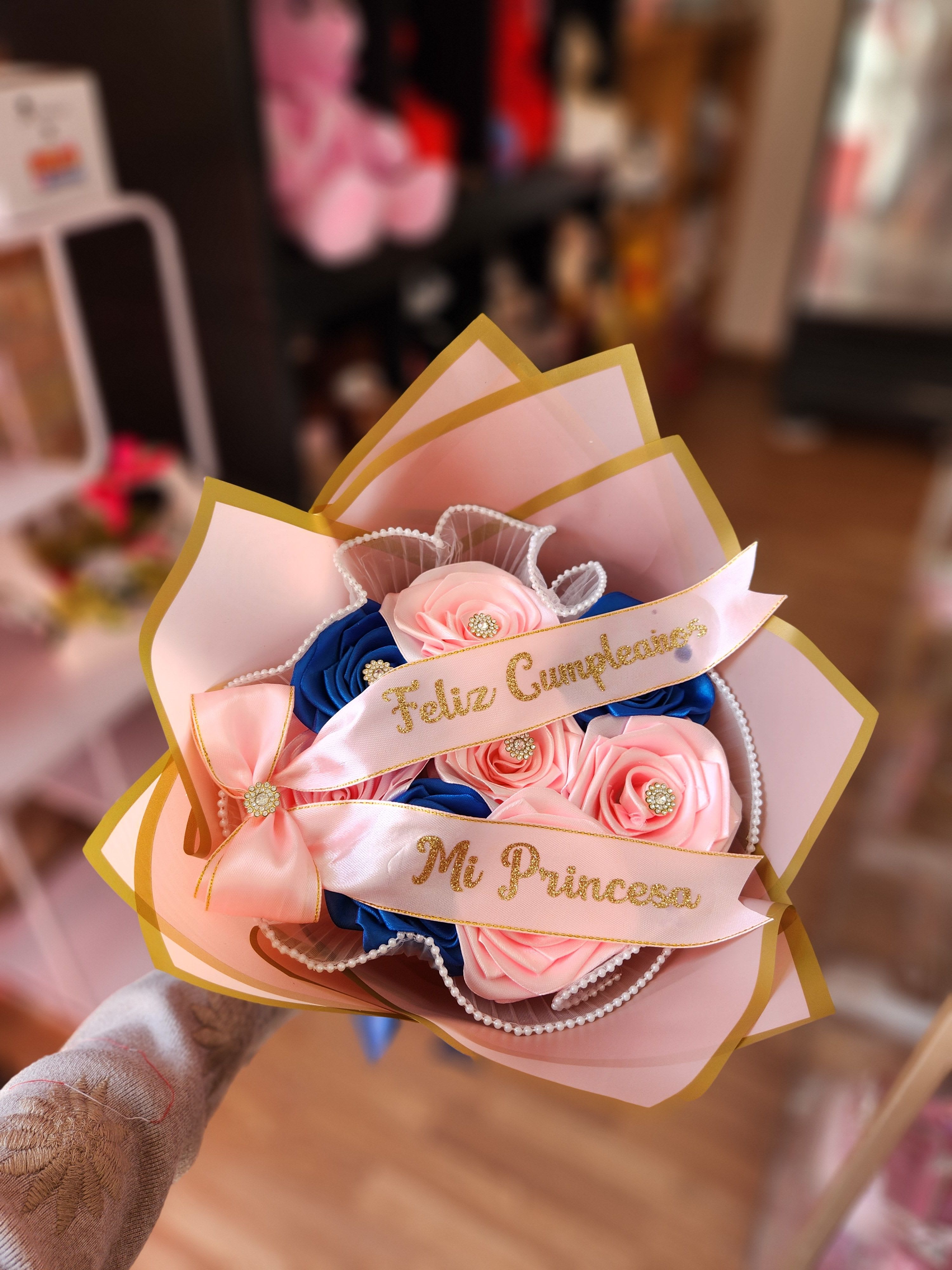 Pink and blue rose bouquet with gold-edged wrapping and ribbons
