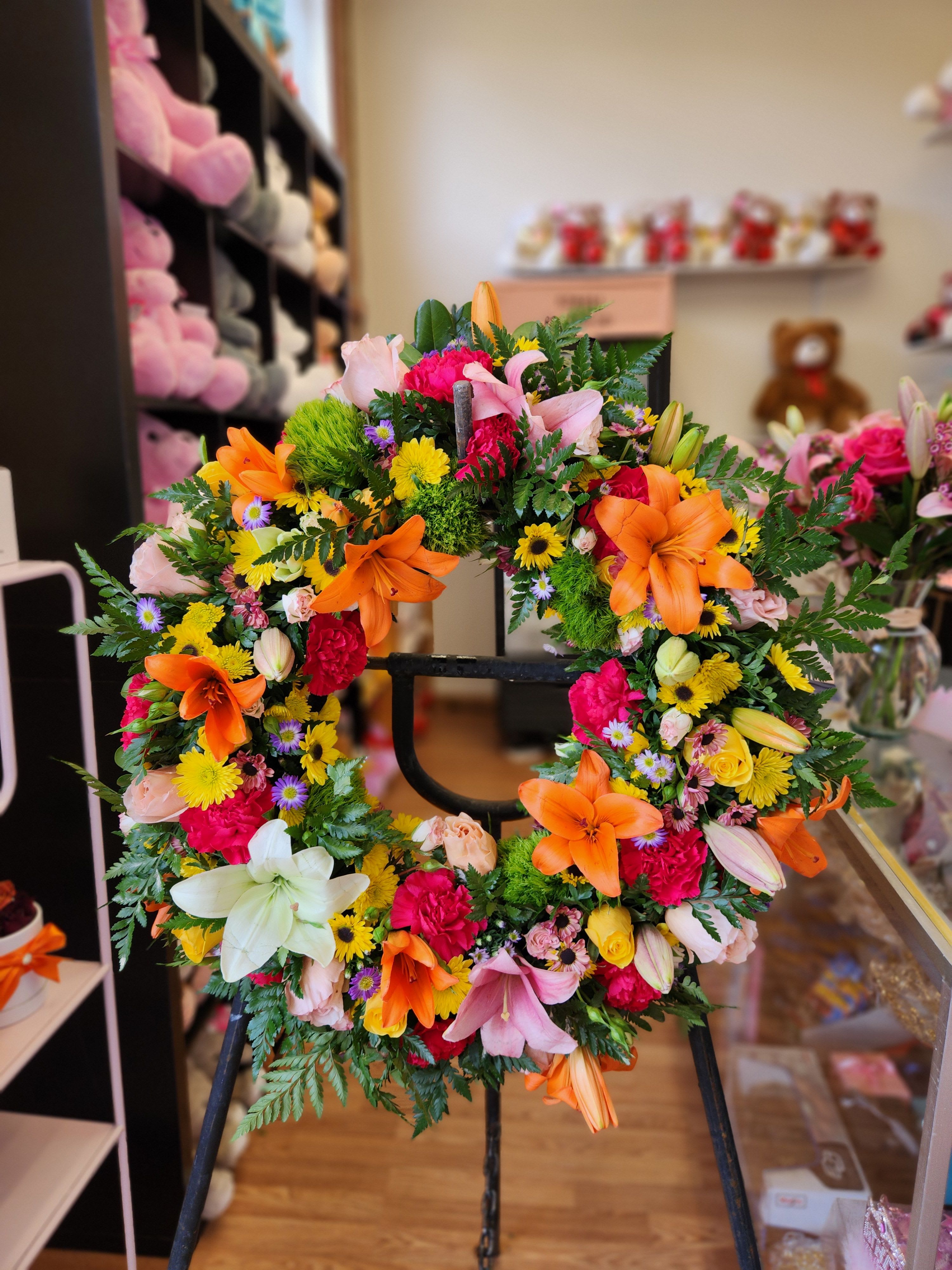 Colorful floral wreath with lilies and mixed blooms on a stand