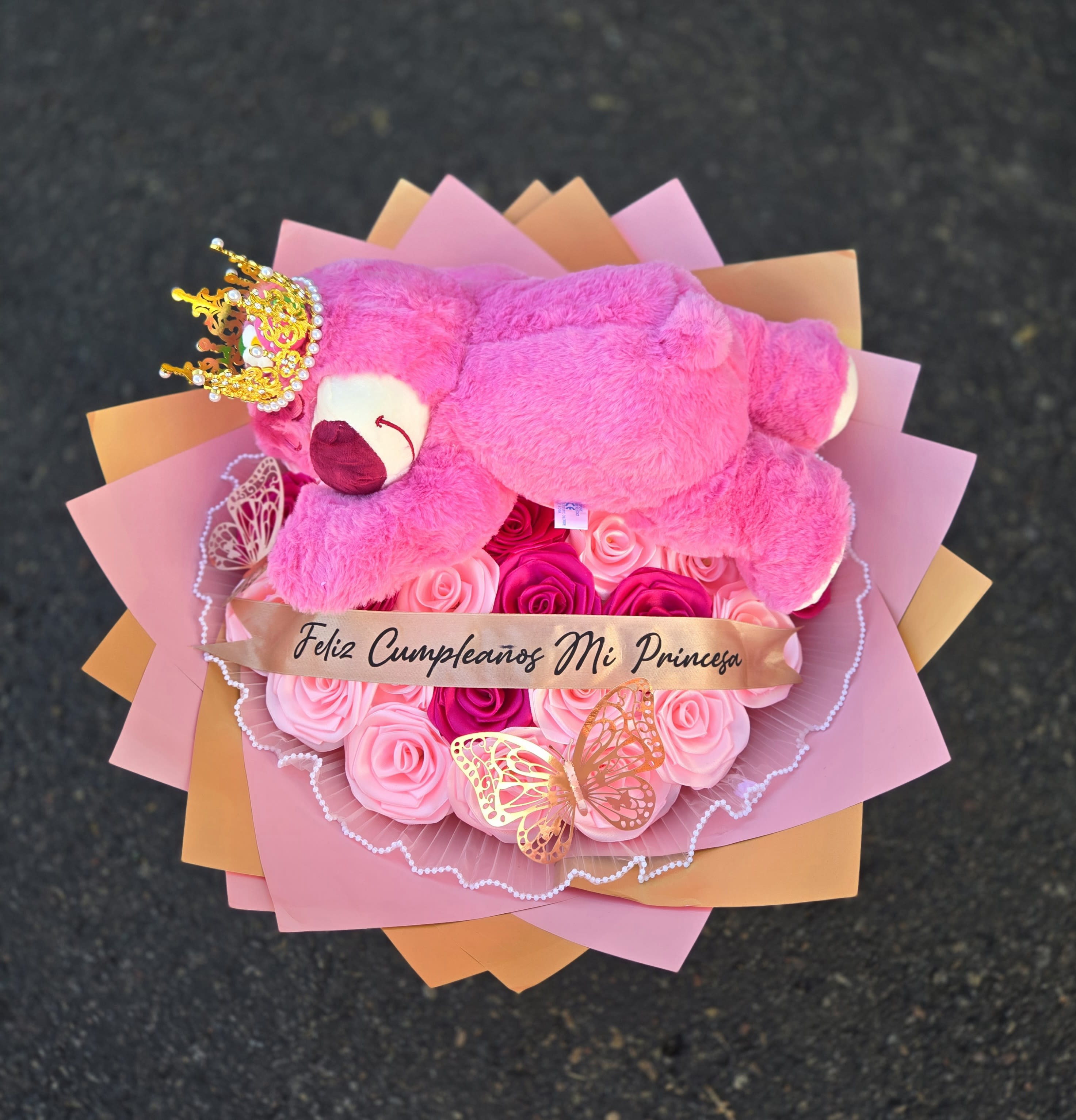 Pink teddy bear on a bouquet of pink roses with a birthday ribbon