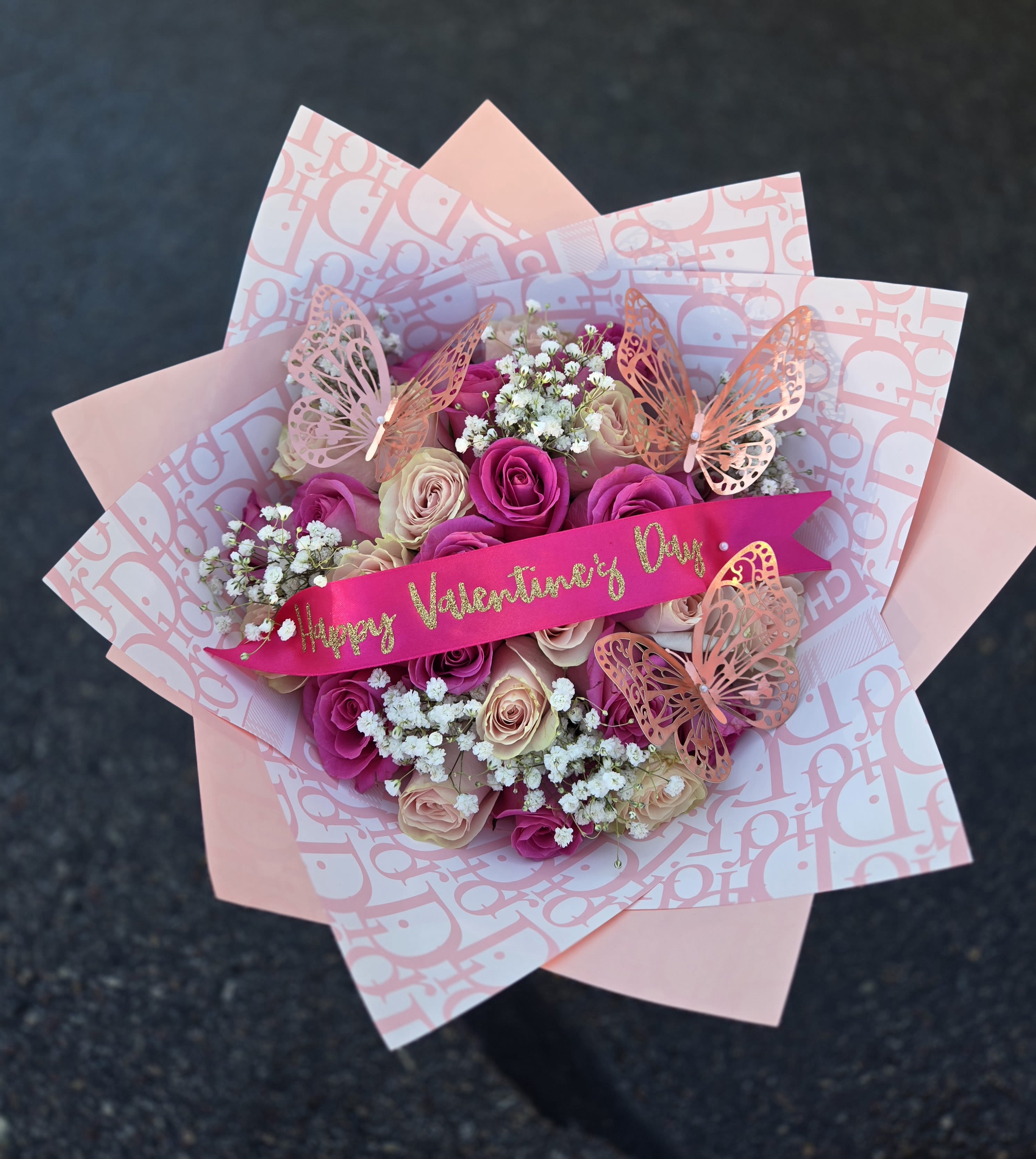 Pink and cream rose bouquet with butterfly decorations and a Valentine ribbon