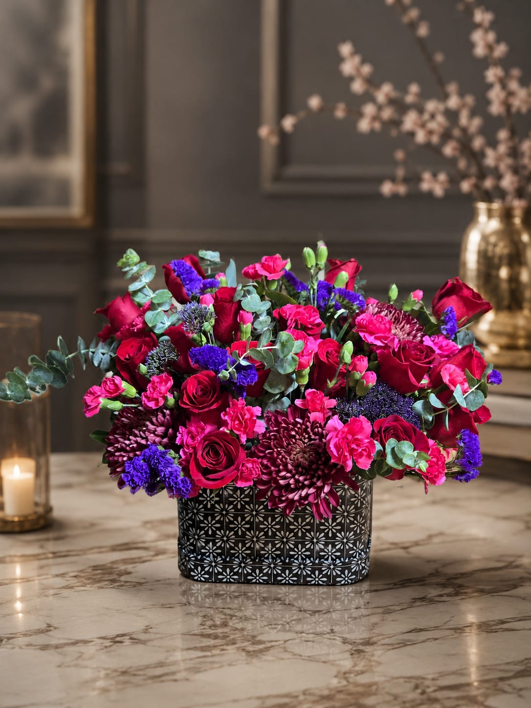 Bright pink and red flower arrangement in a patterned black box
