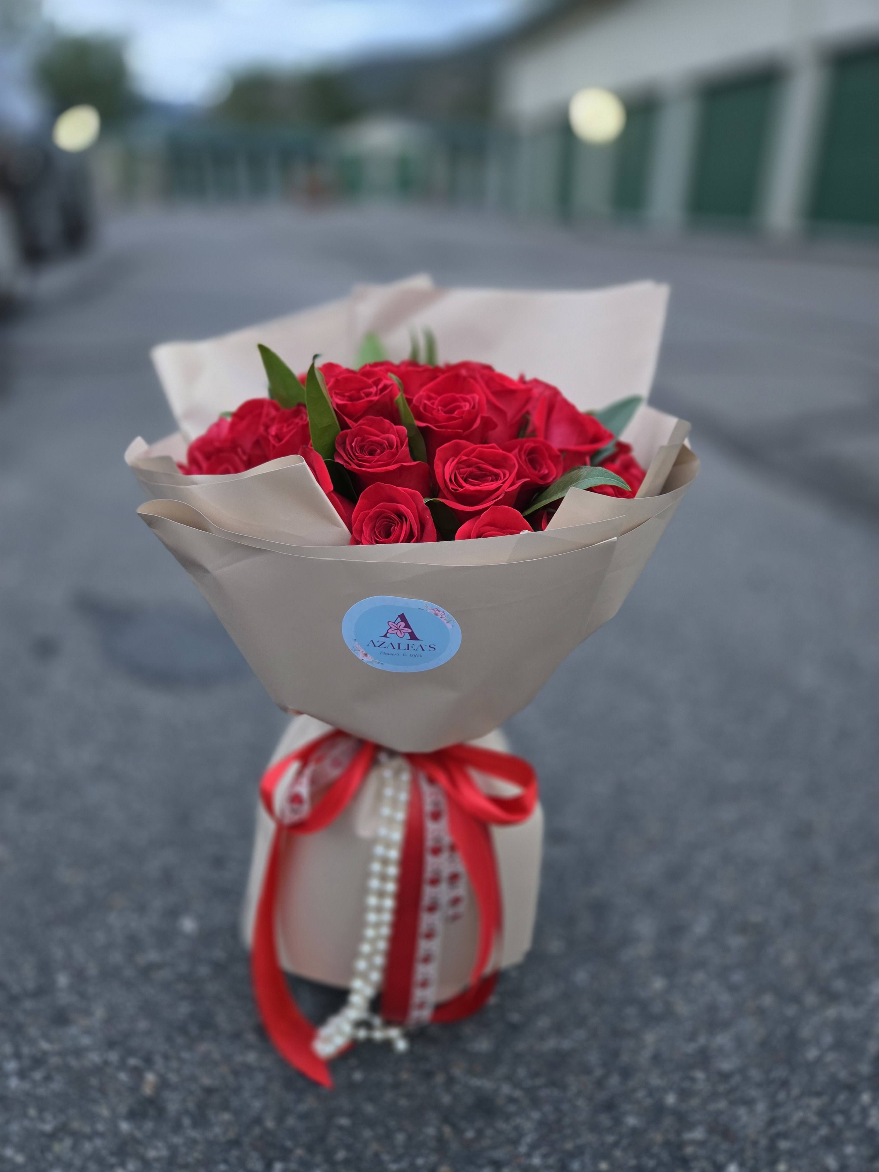Bouquet of red roses wrapped in beige paper with a red ribbon