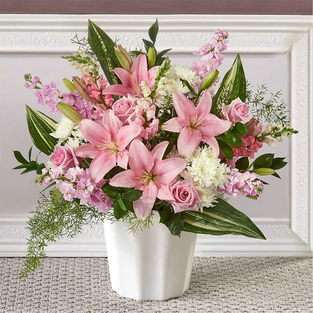 Pink lilies and roses arranged in a white vase