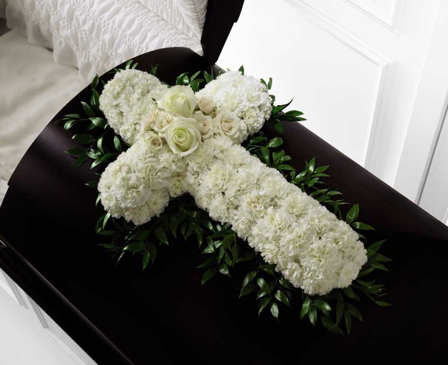 Peaceful Memories Casket Spray - The Peaceful Memories Casket Spray is a gorgeous way to commemorate the faith and devotion of the deceased. White carnations are arranged in the shape of a cross accented in the middle with white roses and spray roses and along the sides with lush greens to create a lovely casket spray that brings peace and solace to those that attend their final farewell.