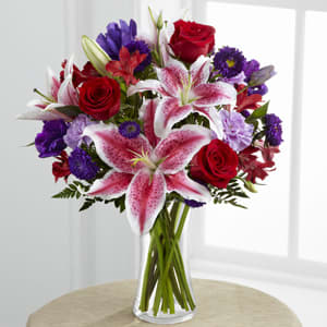 Bouquet of red roses and pink lilies in a clear glass vase