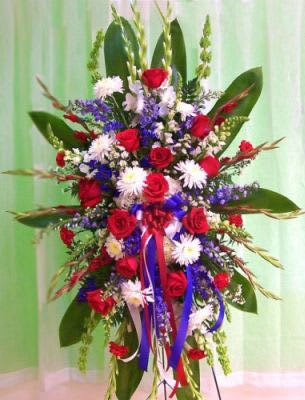 Tall standing floral spray with red roses, white daisies, and blue flowers