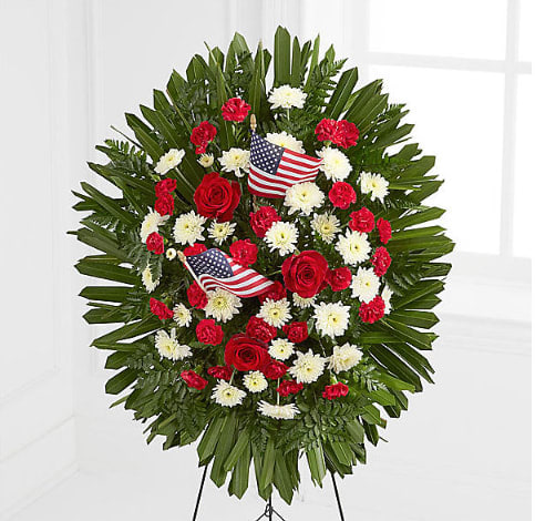 Standing floral wreath with red and white flowers and small American flags