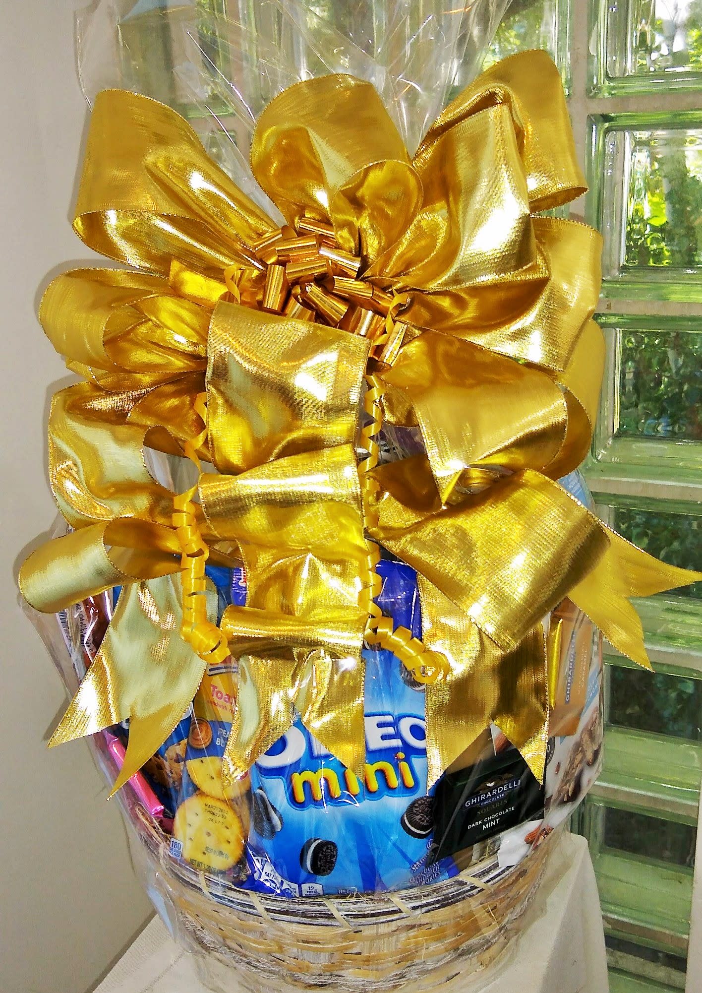 Gift basket wrapped with a large gold bow and assorted snacks