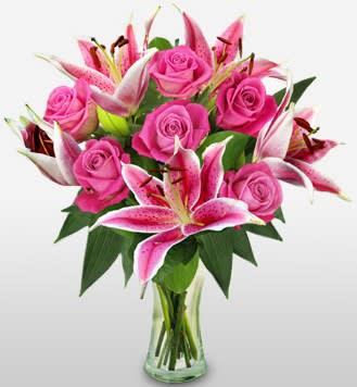 Pink roses and lilies arranged in a clear glass vase