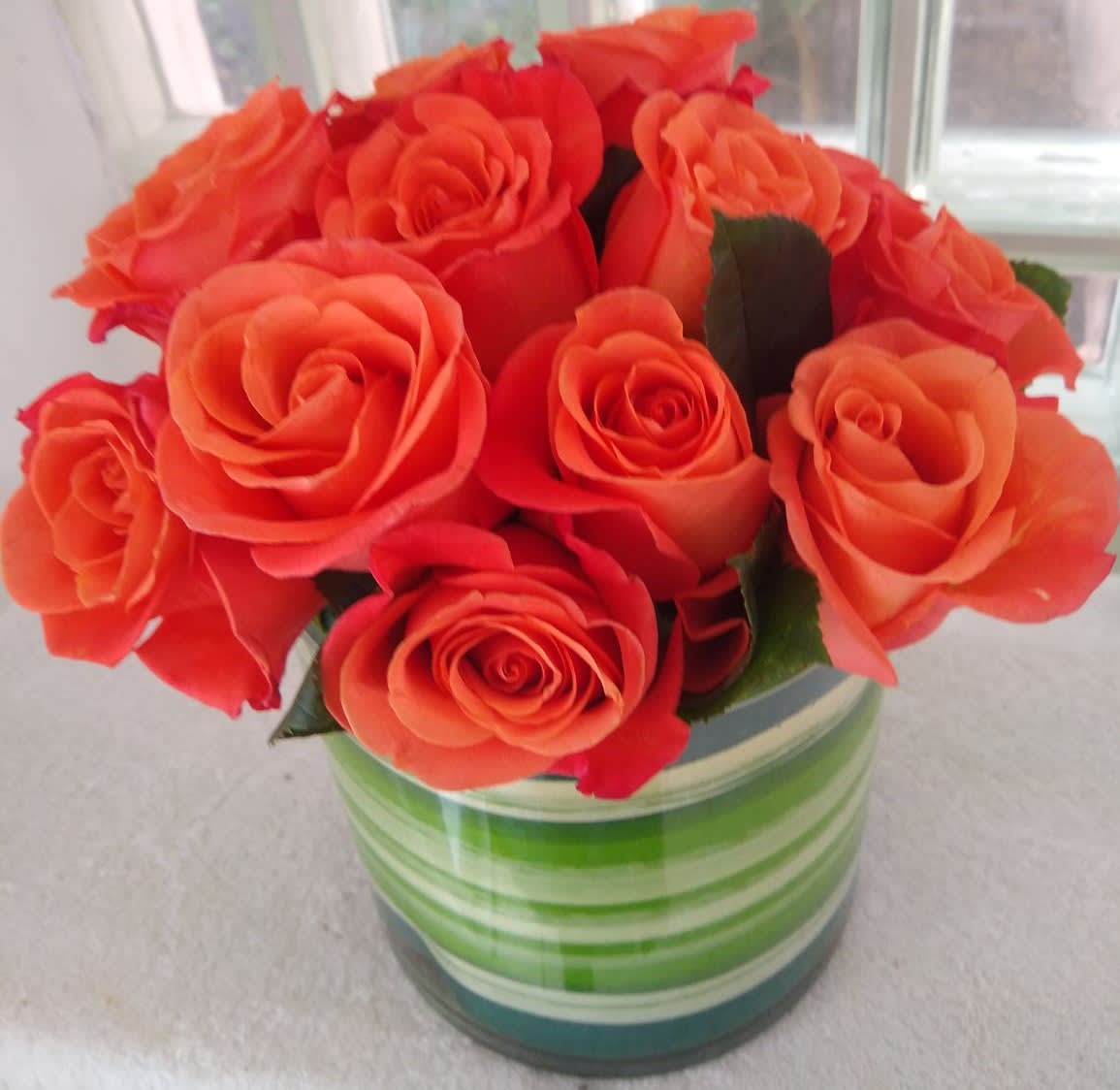 Orange roses arranged in a striped glass vase