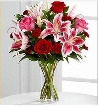 Bouquet of red roses and pink lilies in a clear glass vase