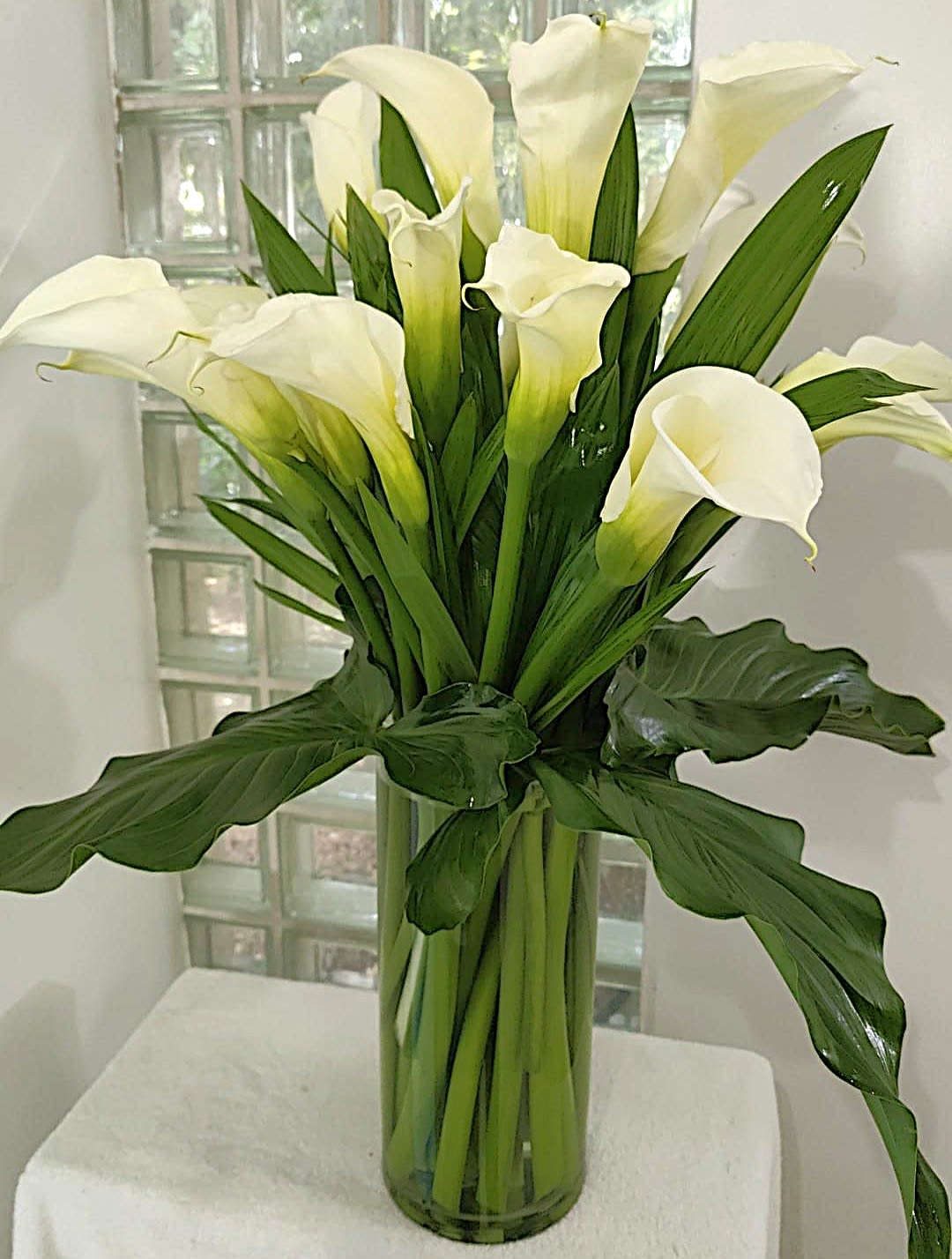 White calla lilies in a tall glass vase