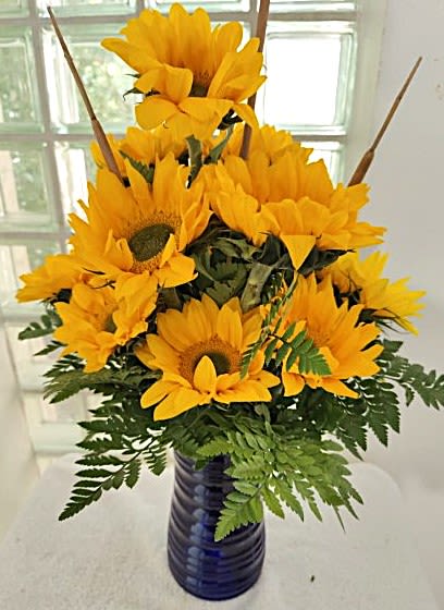 Smiling Sunflowers -- 10 stems of sunflowers - We've mixed bright and cheery sunflowers into a cobalt blue vase for a stunning presentation. IMPORTANT: Your gift will use either the "Teddy Bear" sunflowers with the light brown center (pictured) or the "Van Gogh" sunflowers with a dark brown center, whichever is the freshest and most vibrant on the day of delivery. 