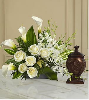 The  At Peace Arrangement - This extraordinary mixed flower bouquet is an excellent choice for creating a beautiful, serene and reverential setting for an urn containing the cremated remains of the deceased. The asymmetrical arrangement is hand-arranged with Dendrobium orchids, roses, calla lilies, and lush, complementary greenery in a low silvery plastic rectangular container. Beautiful on its own or to enhance a display of a meaningful memento, photograph or candle. 