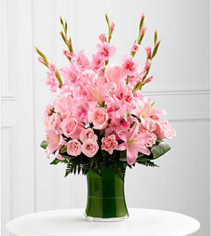 The FTD® Lovely Tribute™ Bouquet - The FTD® Lovely Tribute™ Bouquet is a warm and blushing display of peace and beauty, set to honor the deceased and bring comfort to family and friends. Pink gladiolus, pale pink roses, pink spray roses, pink Asiatic liles and an assortment of lush greens create a sophisticated arrangement seated in a clear glass gathering vase, symbolizing your heartfelt love and sympathy. GOOD bouquet includes 18 stems. Approximately 27"H x 17"W. BETTER bouquet includes 26 stems. Approximately 28"H x 19"W. BEST bouquet includes 33 stems. Approximately 30"H x 22"W. Your purchase includes a complimentary personalized gift message.