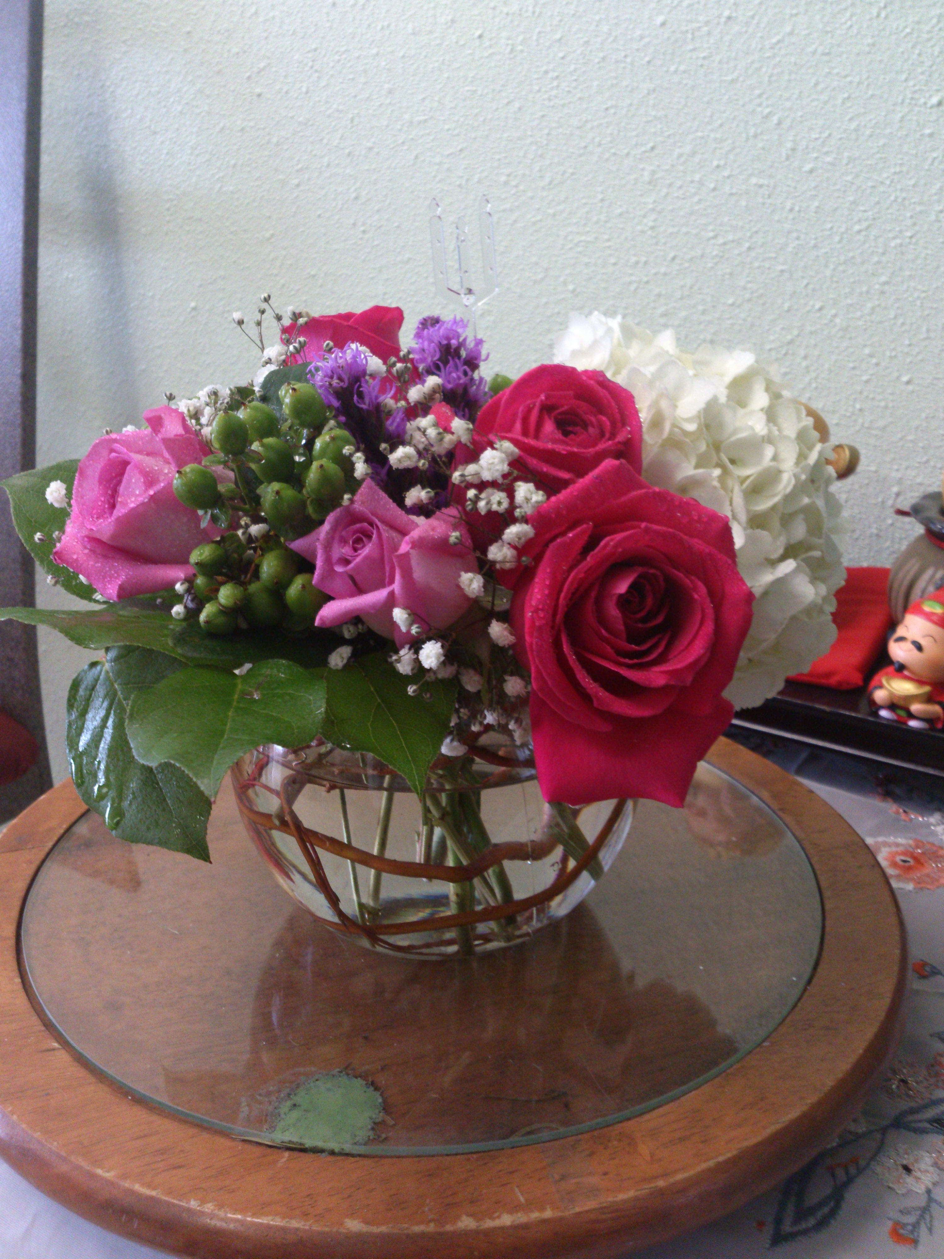 Soft Enchantment Bouquet - This is a simple bouquet of floral elegance and grace. Hot pink and lavender roses are set to capture his or her attention arranged amongst white hydrangea and green hypericum berries with lush greens. Presented in a clear glass bubble bowl vase, this bouquet creates a wonderful gift of blooming beauty.