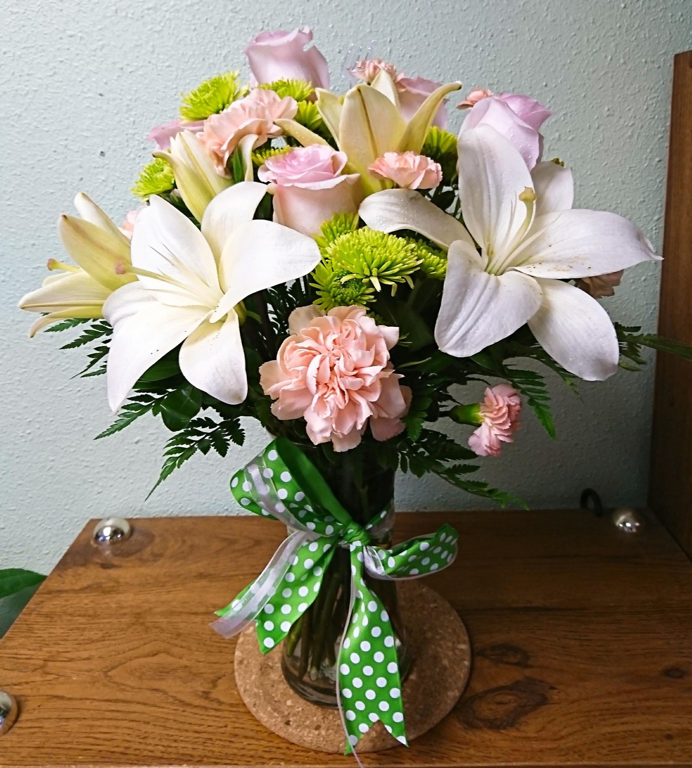 Bouquet of white lilies, pink roses, and carnations in a glass vase