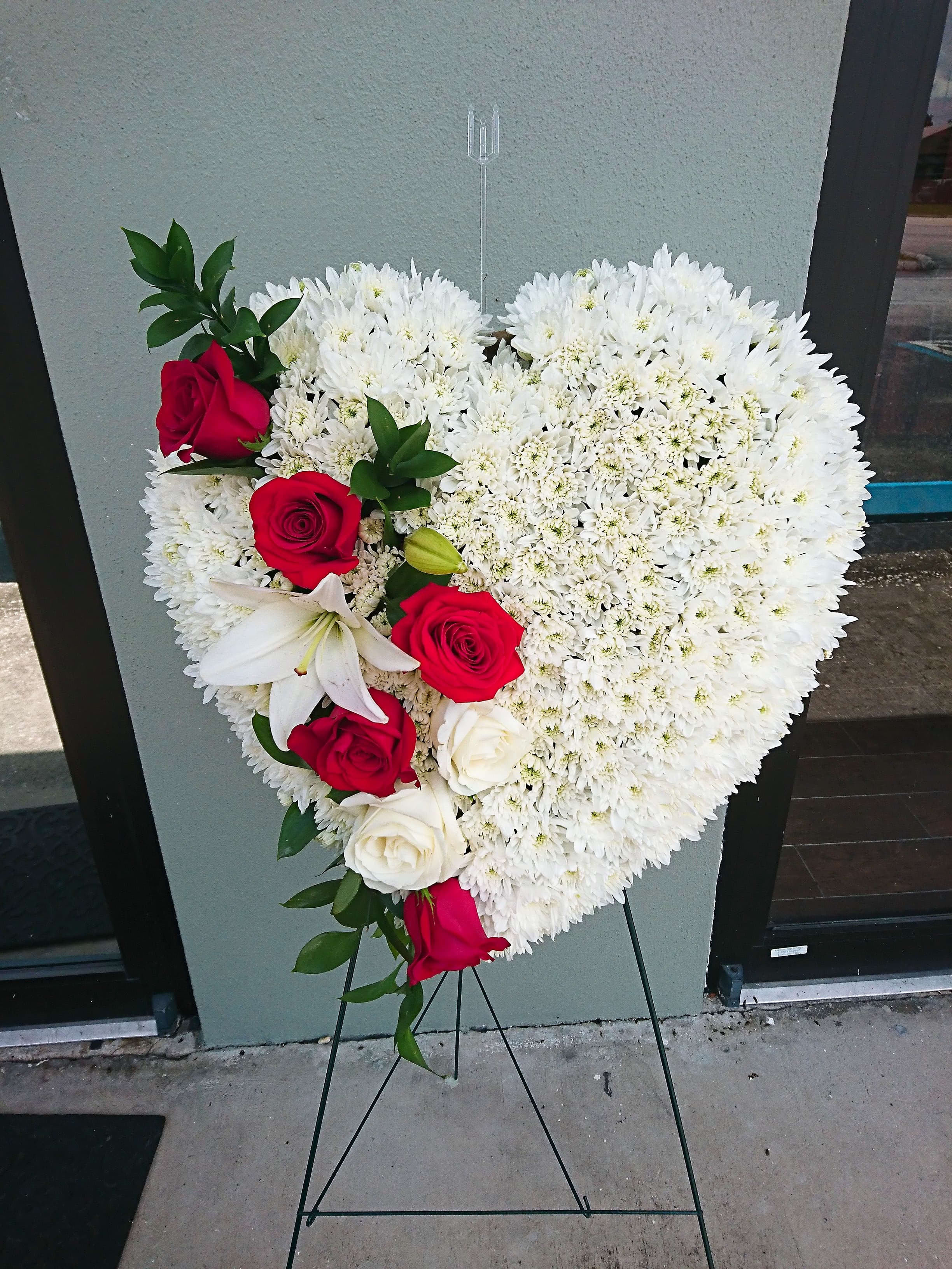 Heart-shaped floral spray with white blooms and red roses on a stand