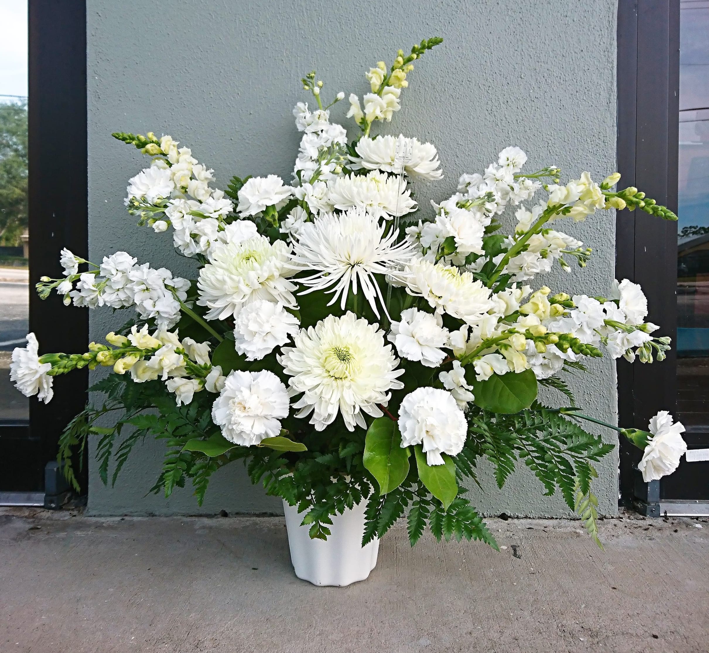 White floral arrangement in a white vase with mixed blooms and greenery