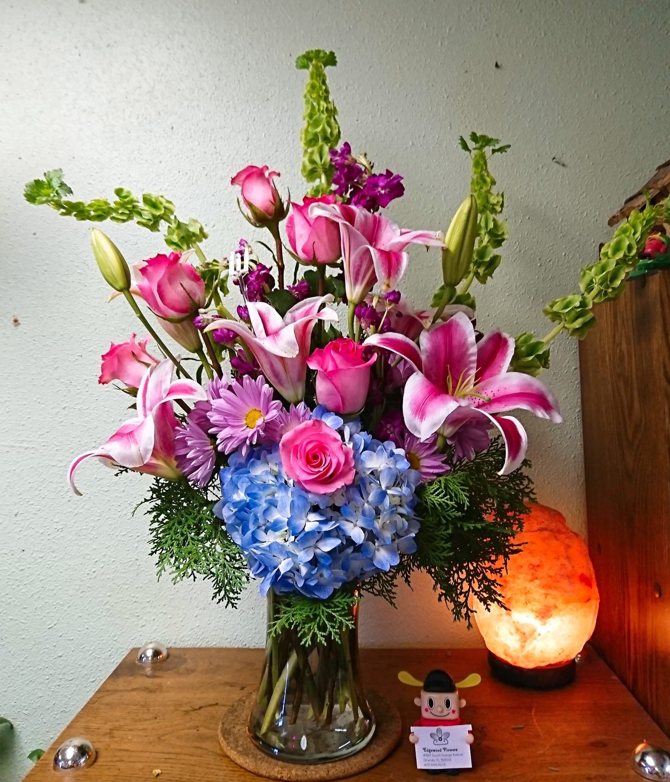 Pink lilies and roses with blue hydrangea in a glass vase