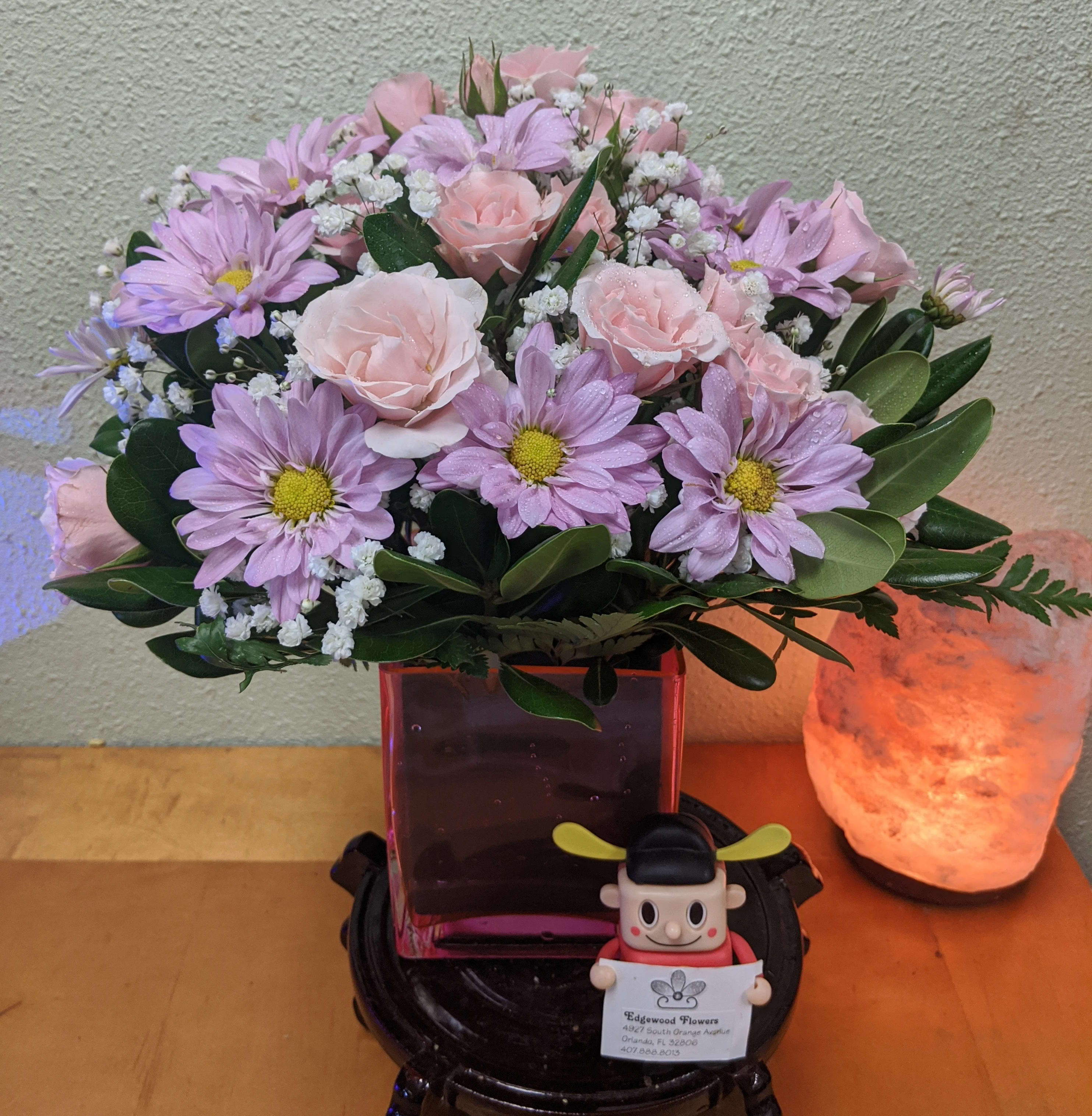 Pink roses and lavender daisies in a square glass vase