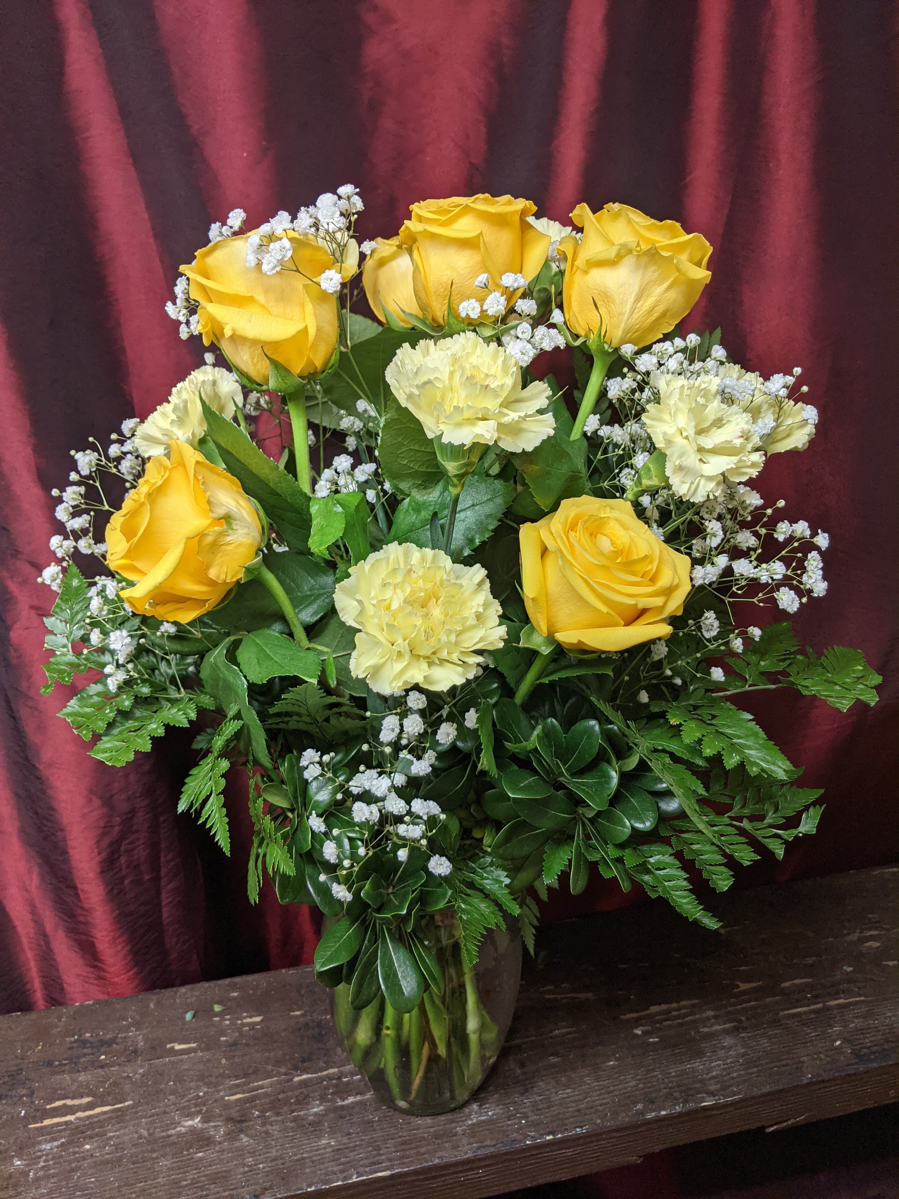 Yellow roses and pale carnations in a glass vase