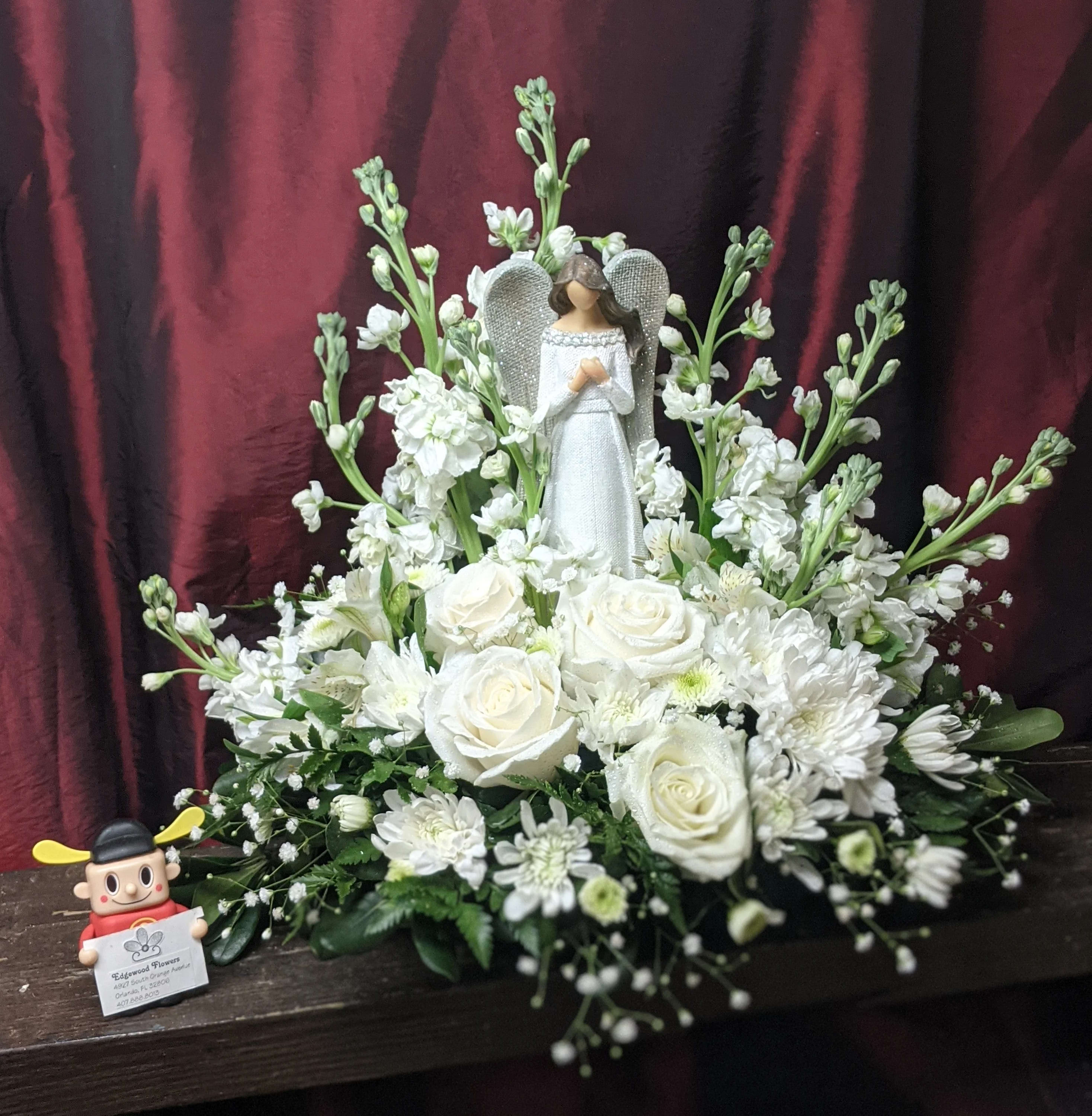 Guardian Angel Bouquet - A beautiful resin Angel figurine that becomes a table topper after the floral use. All white flowers such as roses, stocks, alstroemerias, and chrysanthemums are used for the perfect heaven-sent bouquet to comfort someone in need.