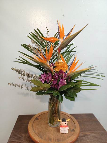 Tropical flower arrangement with orange bird-of-paradise in a glass vase