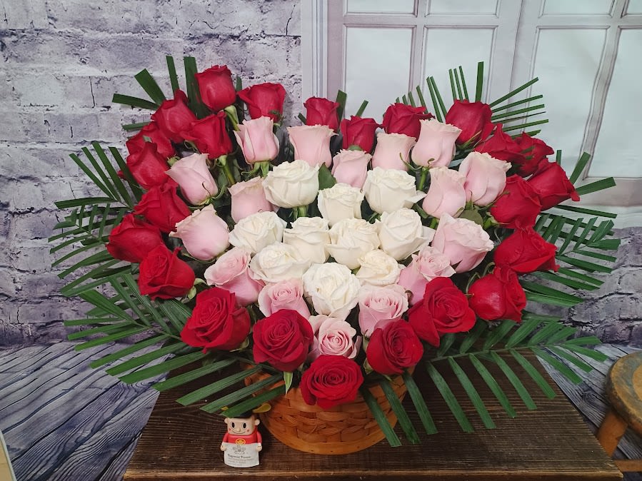 Heart-shaped bouquet of red, pink, and white roses in a basket