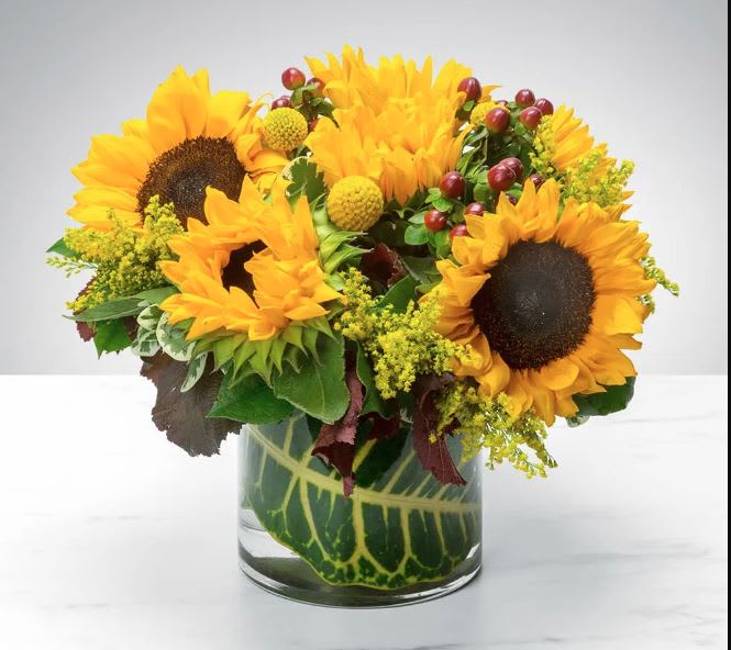 Sunflower arrangement in a clear glass vase with yellow accents