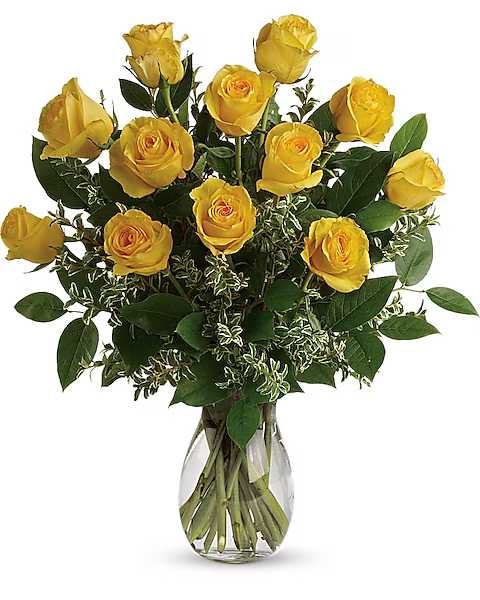 Yellow roses arranged in a clear glass vase with mixed greenery.