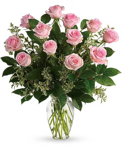 Pink roses arranged in a clear glass vase with mixed greenery