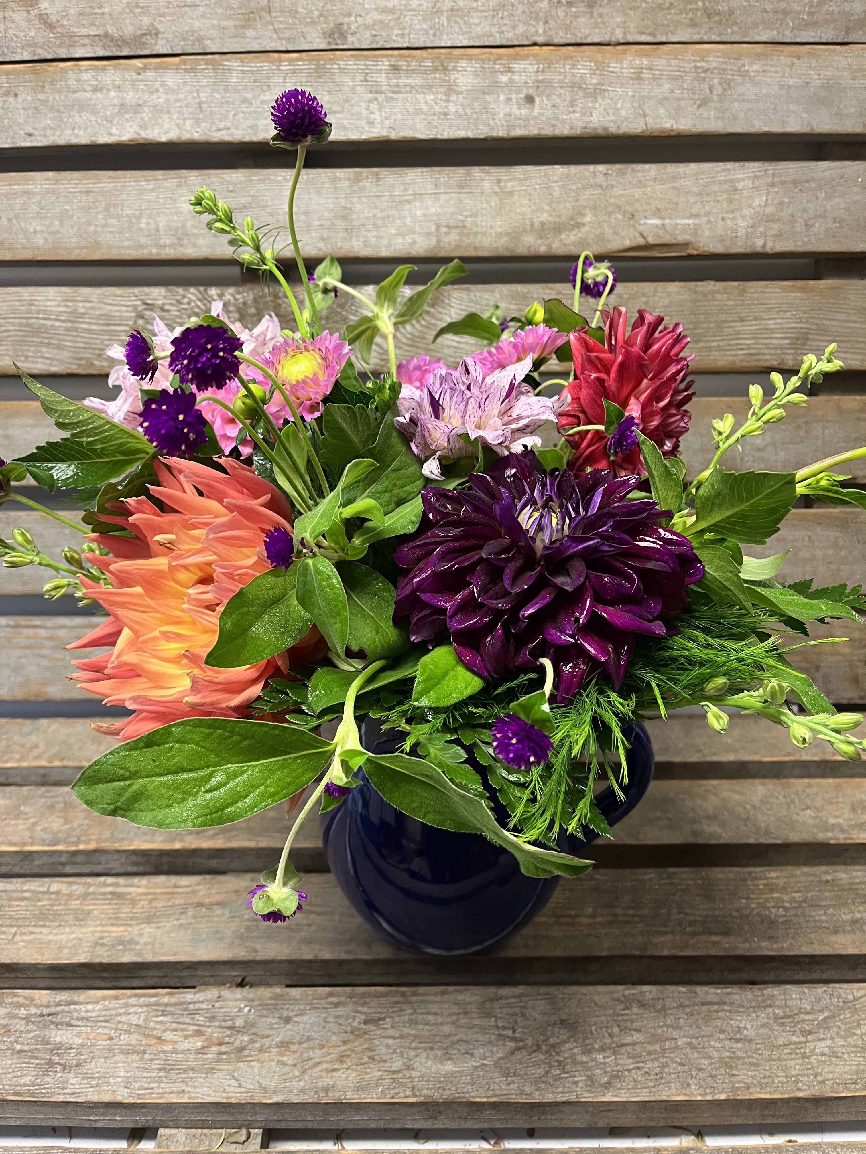 Colorful mixed bouquet in a dark vase with purple, pink, and coral blooms