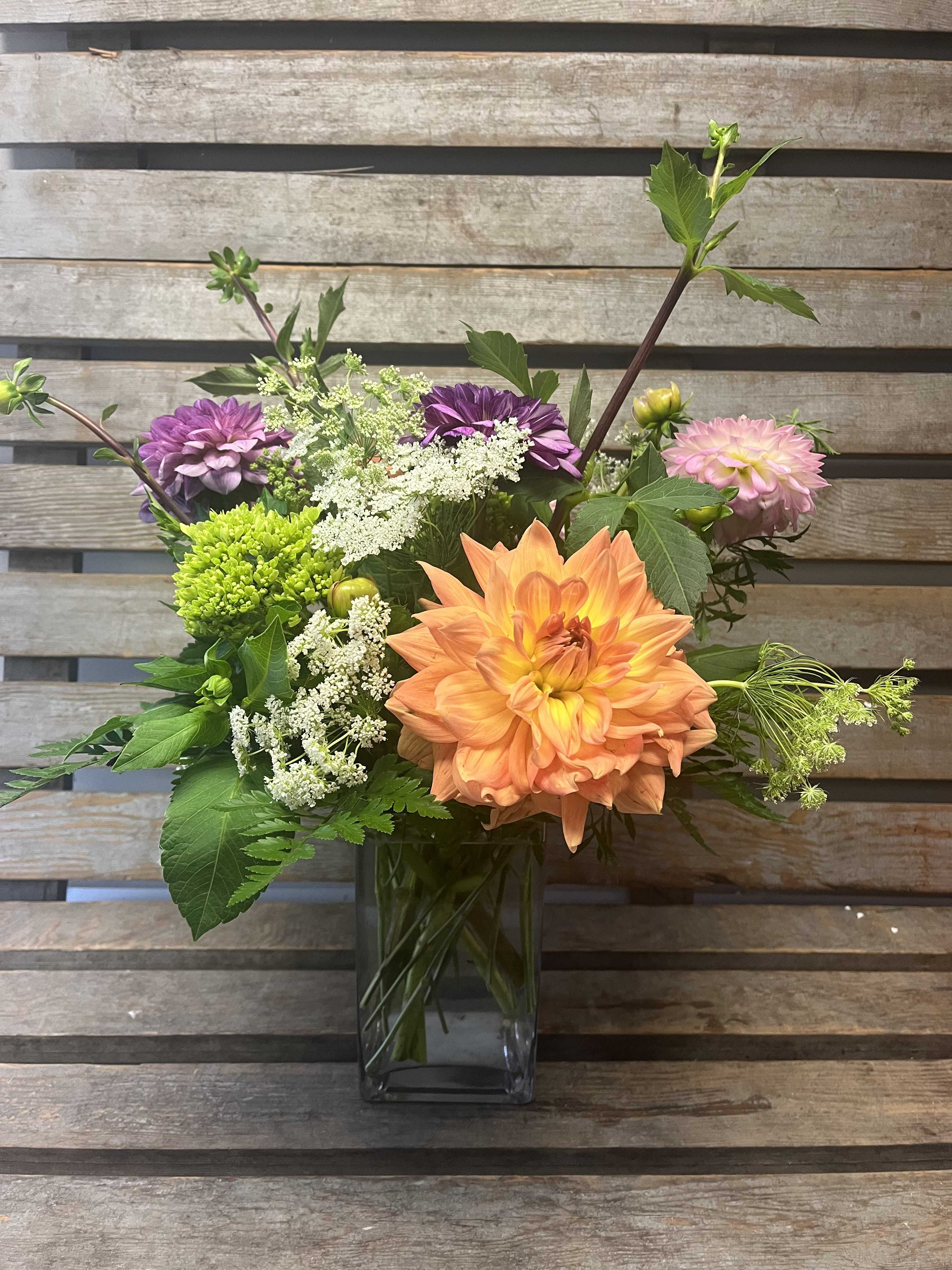 Mixed bouquet in a clear glass vase with orange, pink, and purple blooms