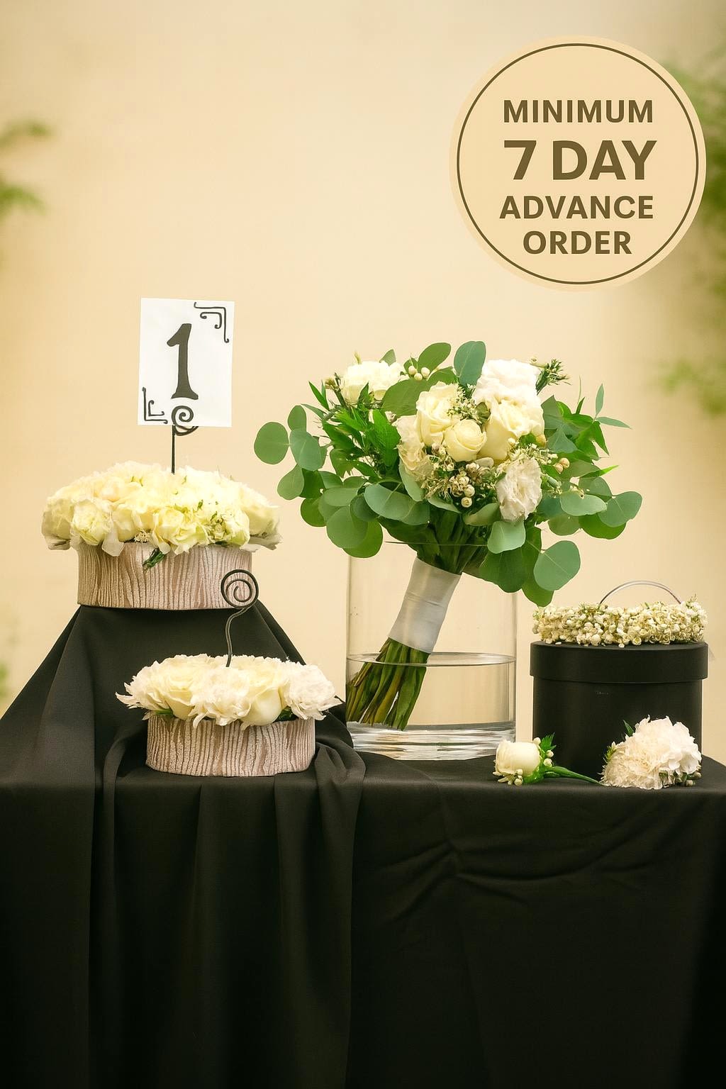 White rose wedding bouquet with matching centerpieces and floral crown on a black-draped table