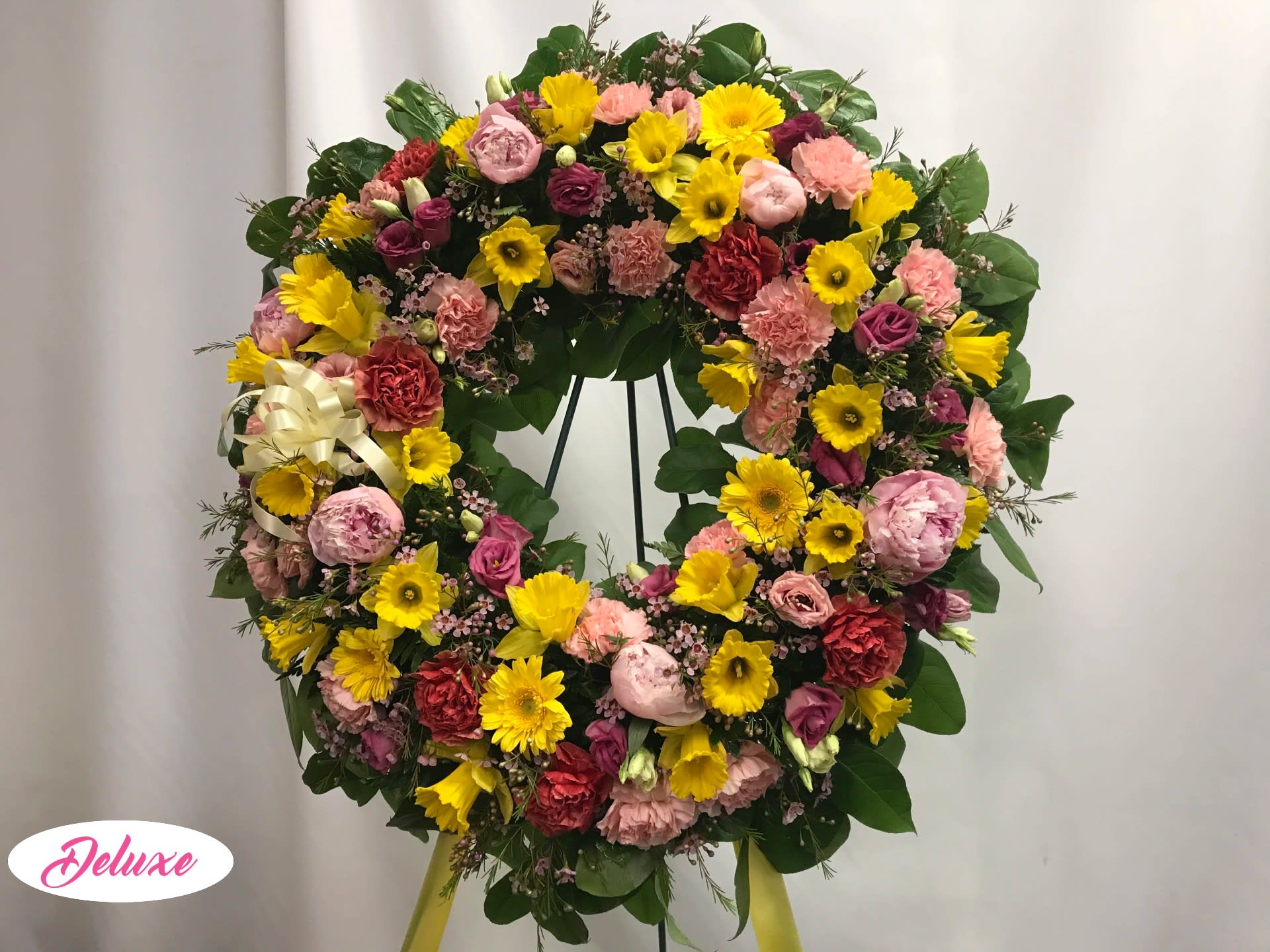 Large circular wreath of pink, yellow, and red flowers on a stand