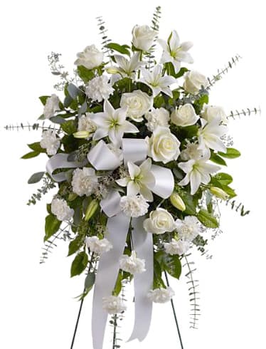 White floral standing spray with lilies, roses, and ribbon