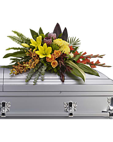 Floral spray on a silver casket with yellow lilies and orange roses