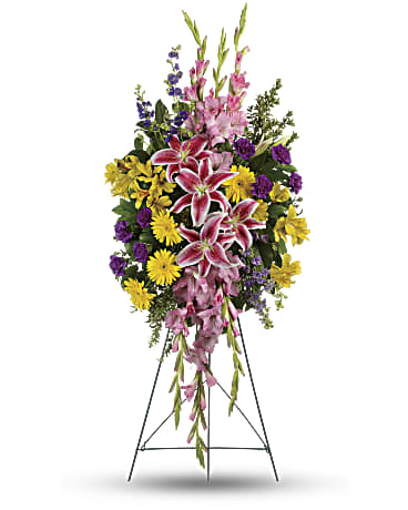 Standing funeral spray with pink lilies, yellow daisies, and purple flowers