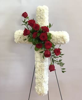 White floral cross with red roses on a stand