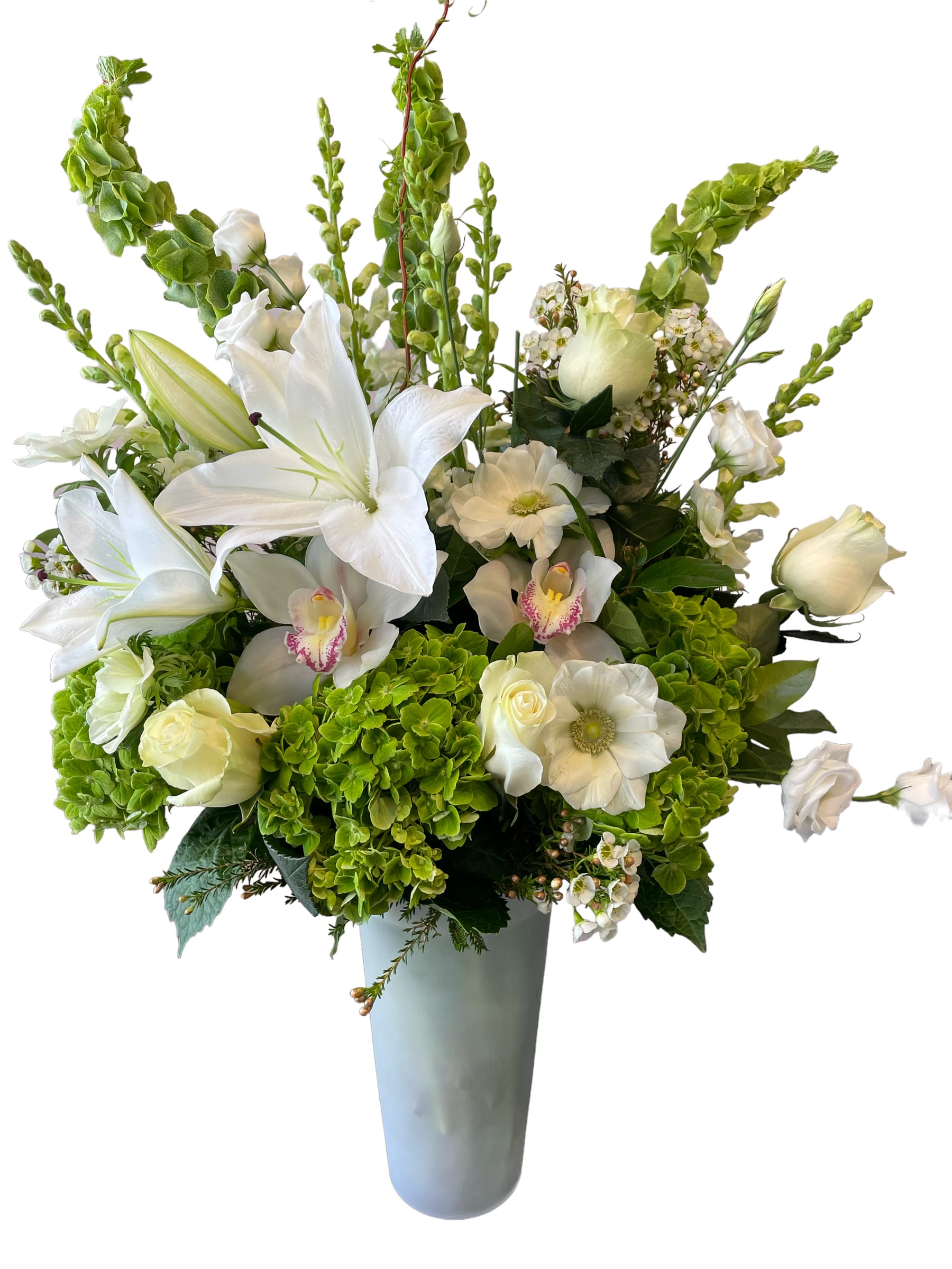 White lilies and orchids in a tall gray vase with green hydrangeas