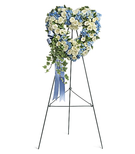 Heart-shaped floral wreath on a standing easel with blue and white flowers
