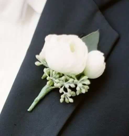White boutonniere with small greenery on a dark suit lapel